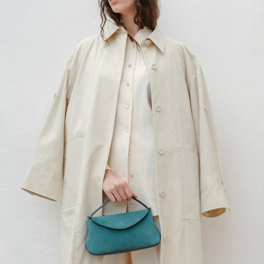 Model holding STOW London's Mini East West in Ocean Teal suede leather featuring gold-coated stainless steel hardware
