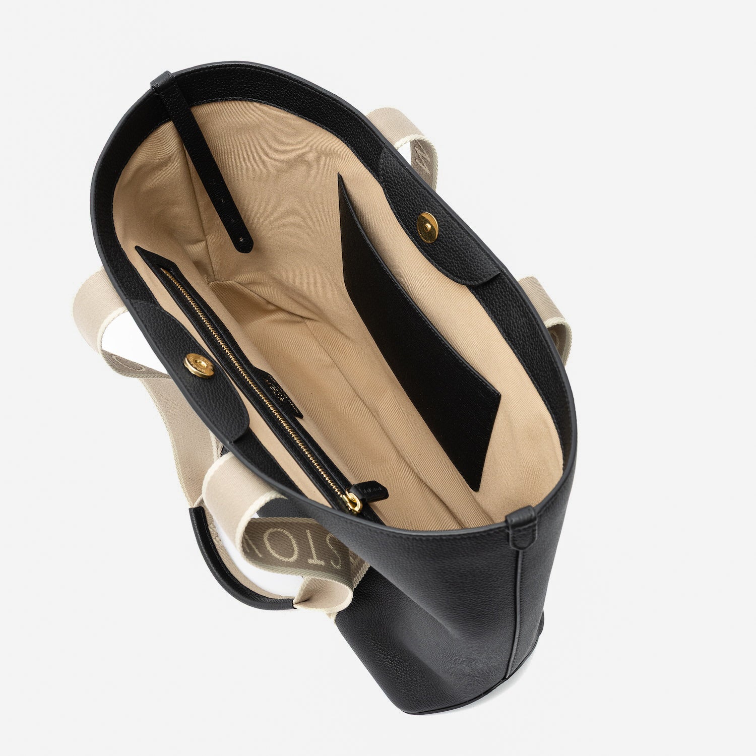 Top view of the interior of STOW London's Nastro Tote bag in Black pebbled leather featuring its zip and slip interior pockets on a light grey background