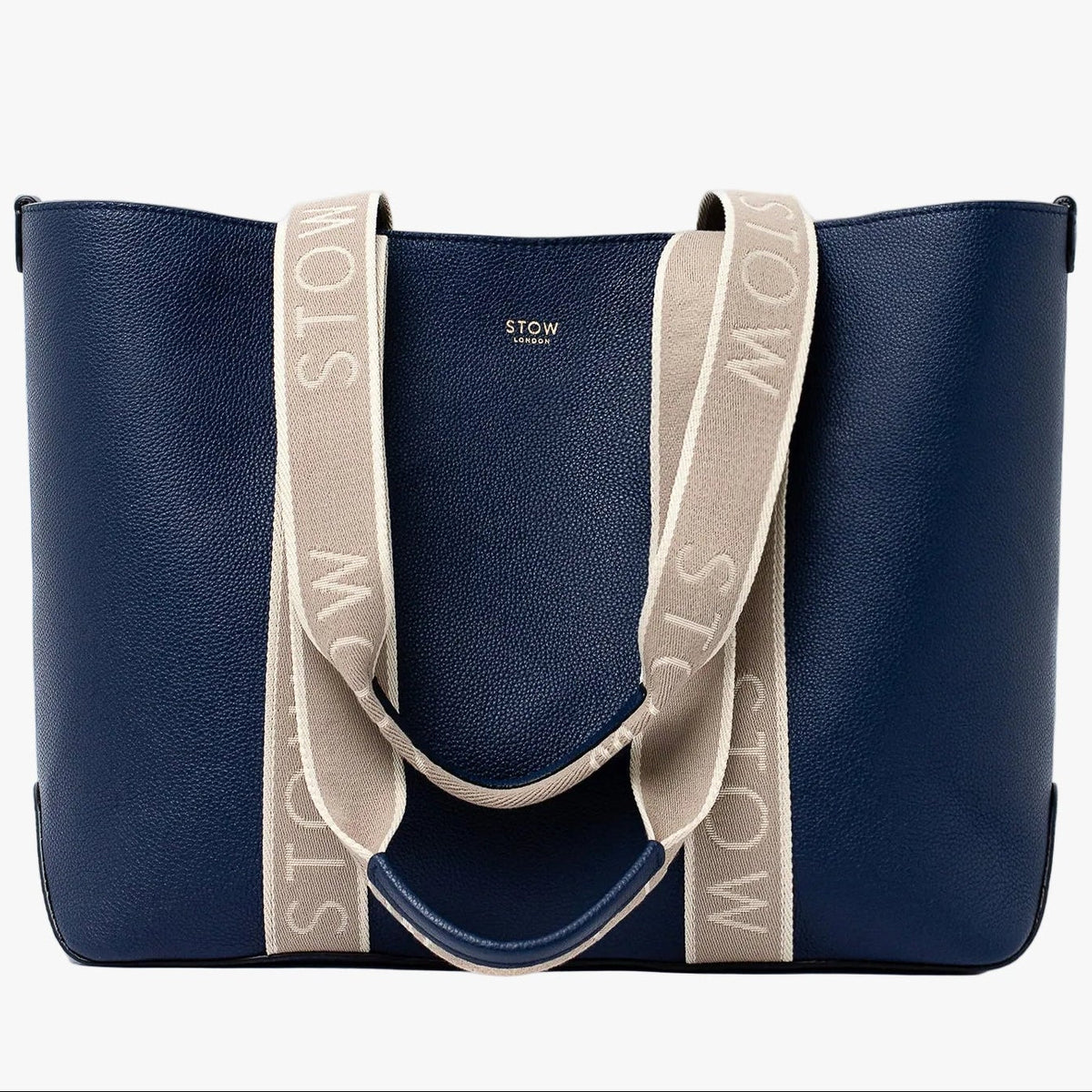 STOW London's Nastro Tote bag in Navy pebbled leather with beige nastro handles featuring 'STOW' branding on a light grey background