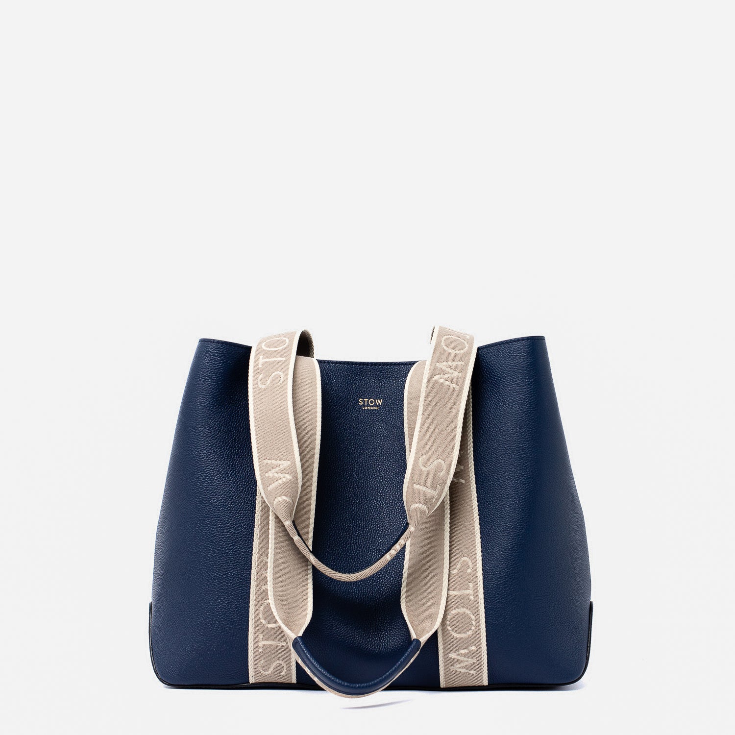 STOW London's Nastro Tote bag in Navy pebbled leather with beige nastro handles featuring 'STOW' branding on a light grey background