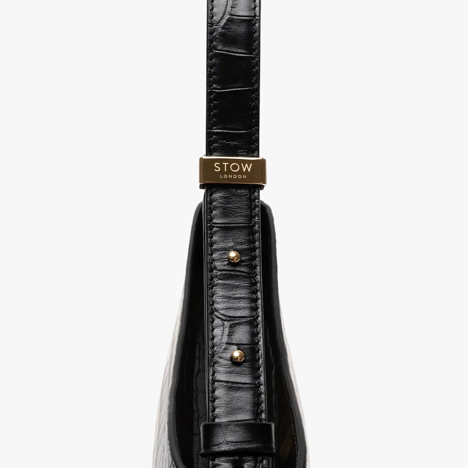 Close up of the gold hardware on the adjustable strap on Stow London's Post Shoulder in Black Embossed Croc leather on a light grey background