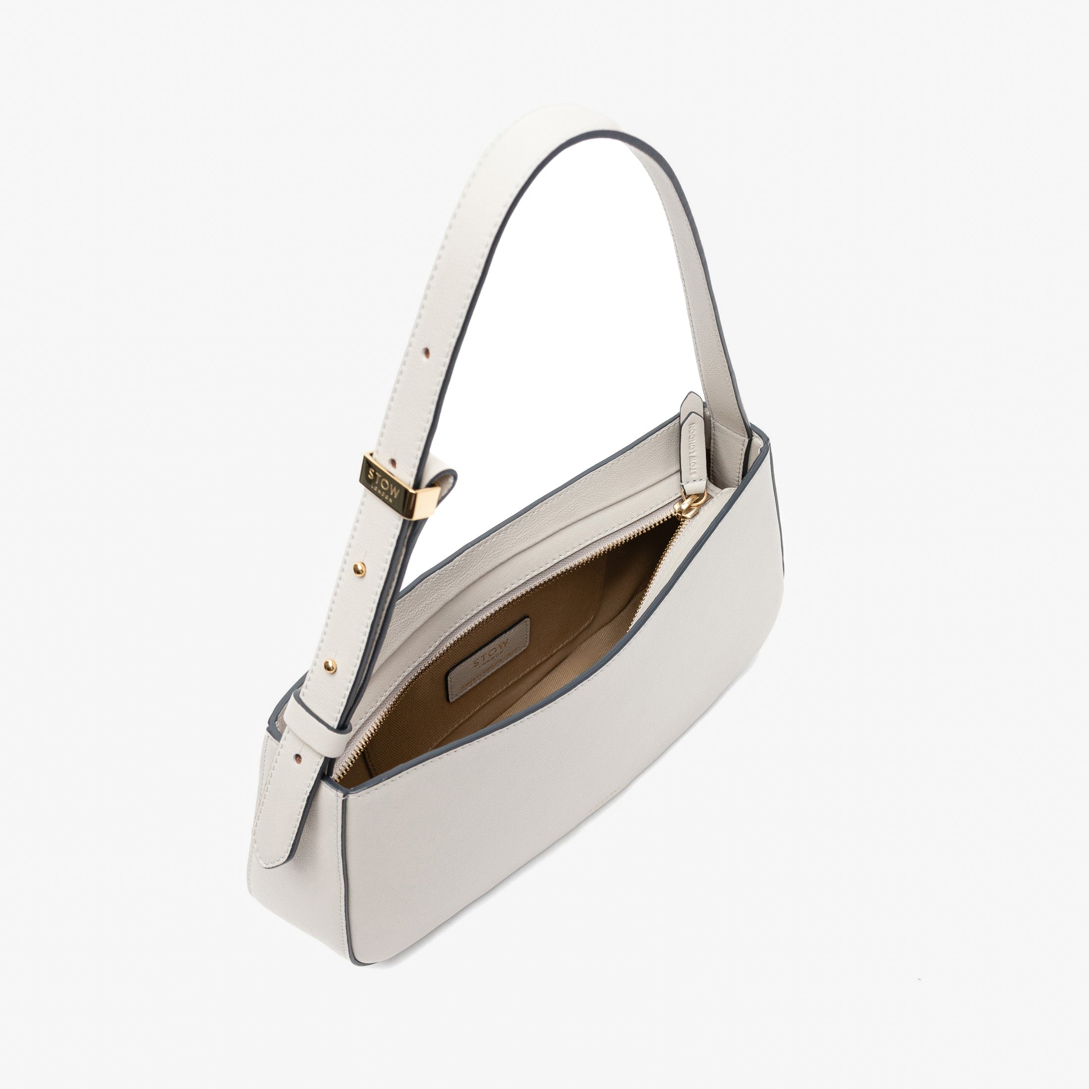 Stow London's Post Shoulder in Cloud Grey smooth leather with zip open showing light beige cotton interior and slip pocket on a light grey background featuring gold-coated stainless steel hardware