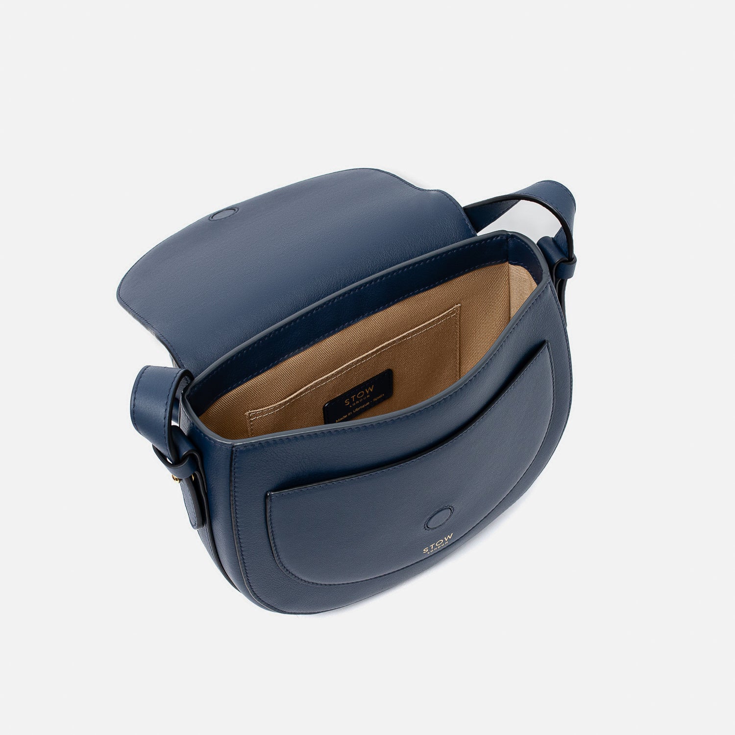 STOW London's Saddle bag in Navy smooth leather with flap open showing light beige interior and slip pocket on a light grey background