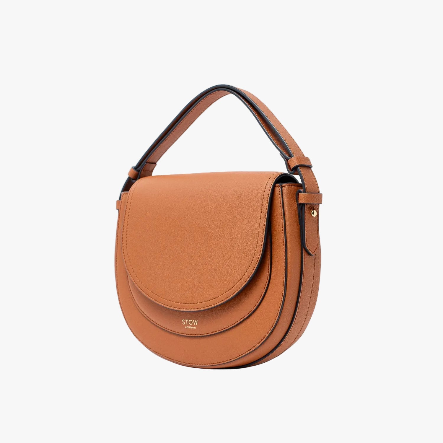 Off-axis view of STOW London's Saddle bag in Earth Tan smooth leather with its short top handle on a light grey background