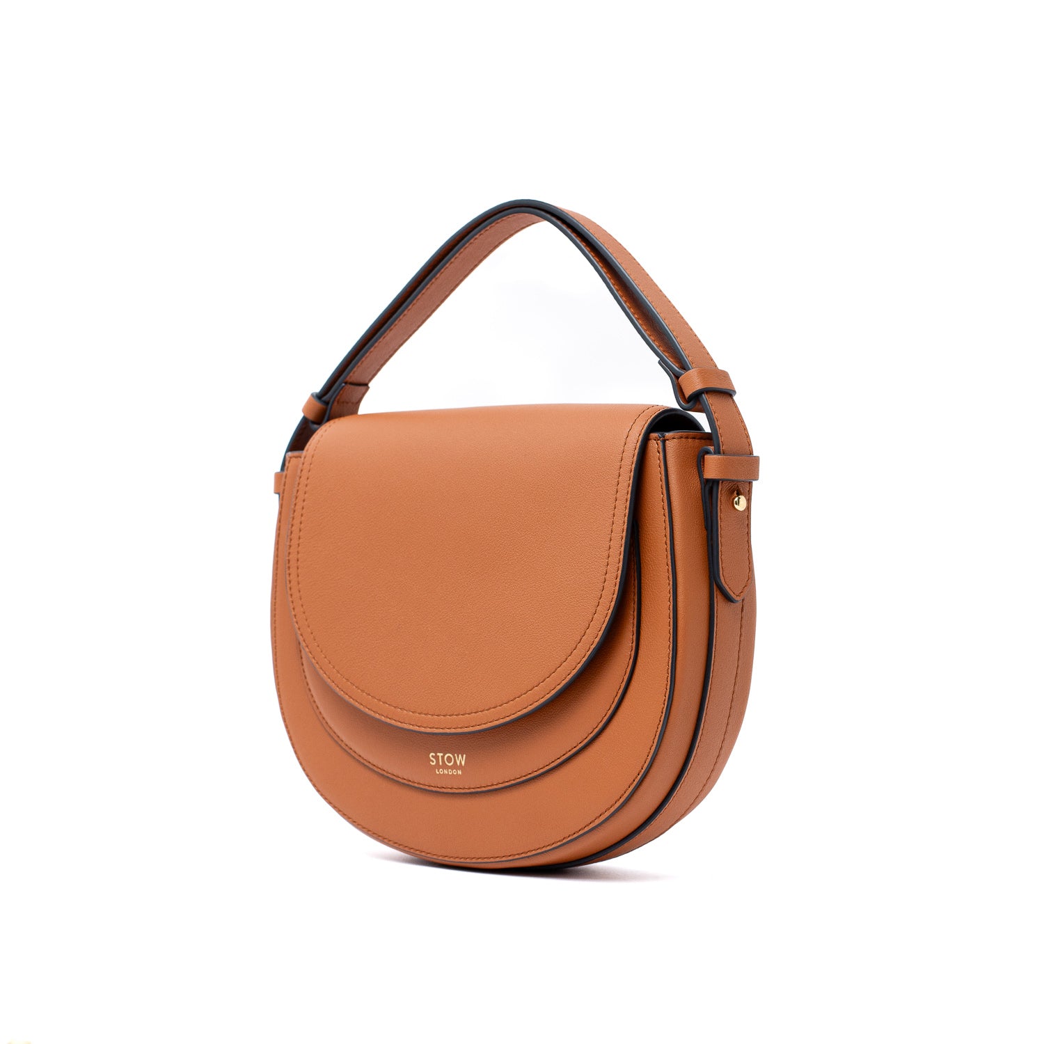 Off-axis view of STOW London's Saddle bag in Earth Tan smooth leather with detachable top handle on a white background
