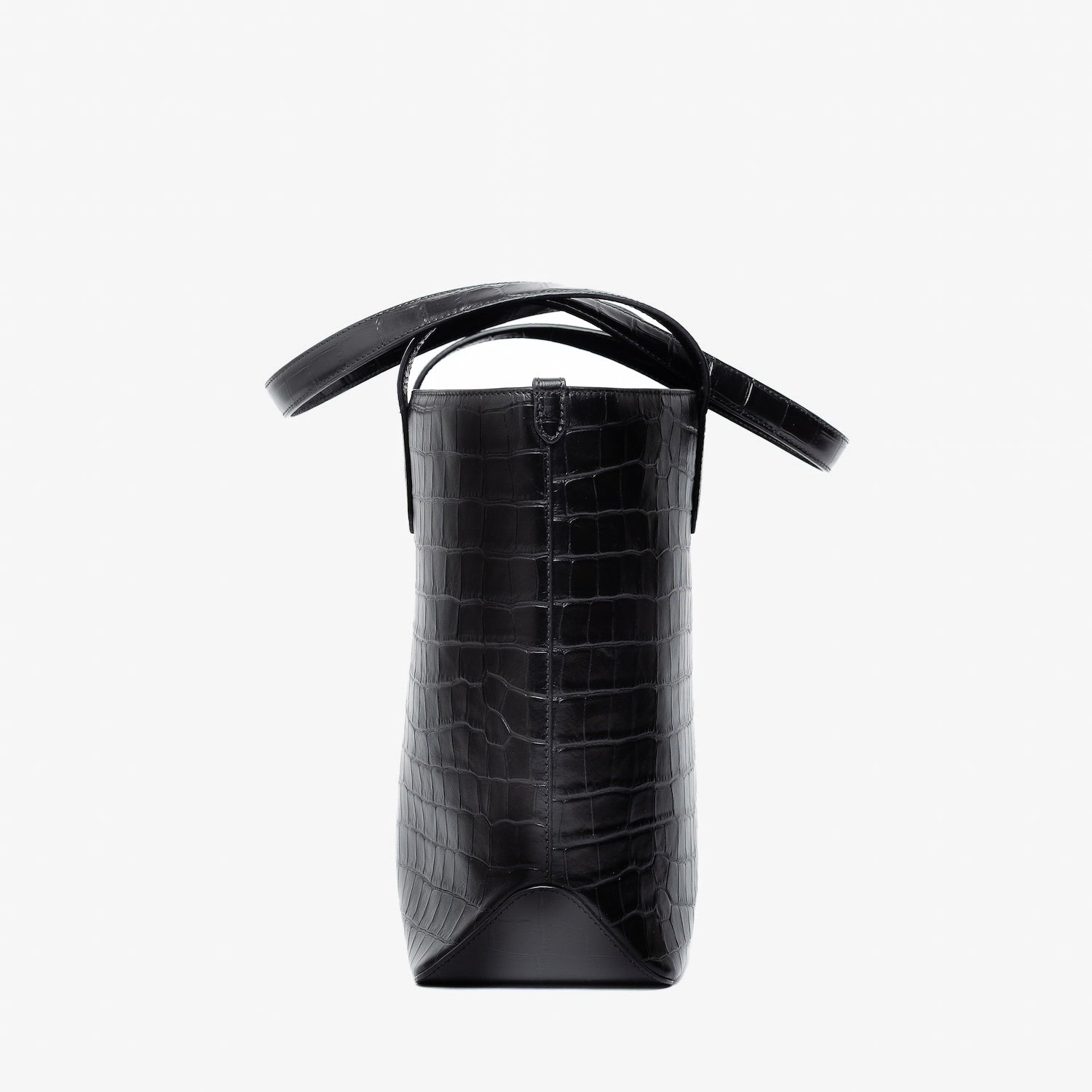 Side view of Stow London's Everyday Tote Bag in Black Embossed Croc leather on a light grey background