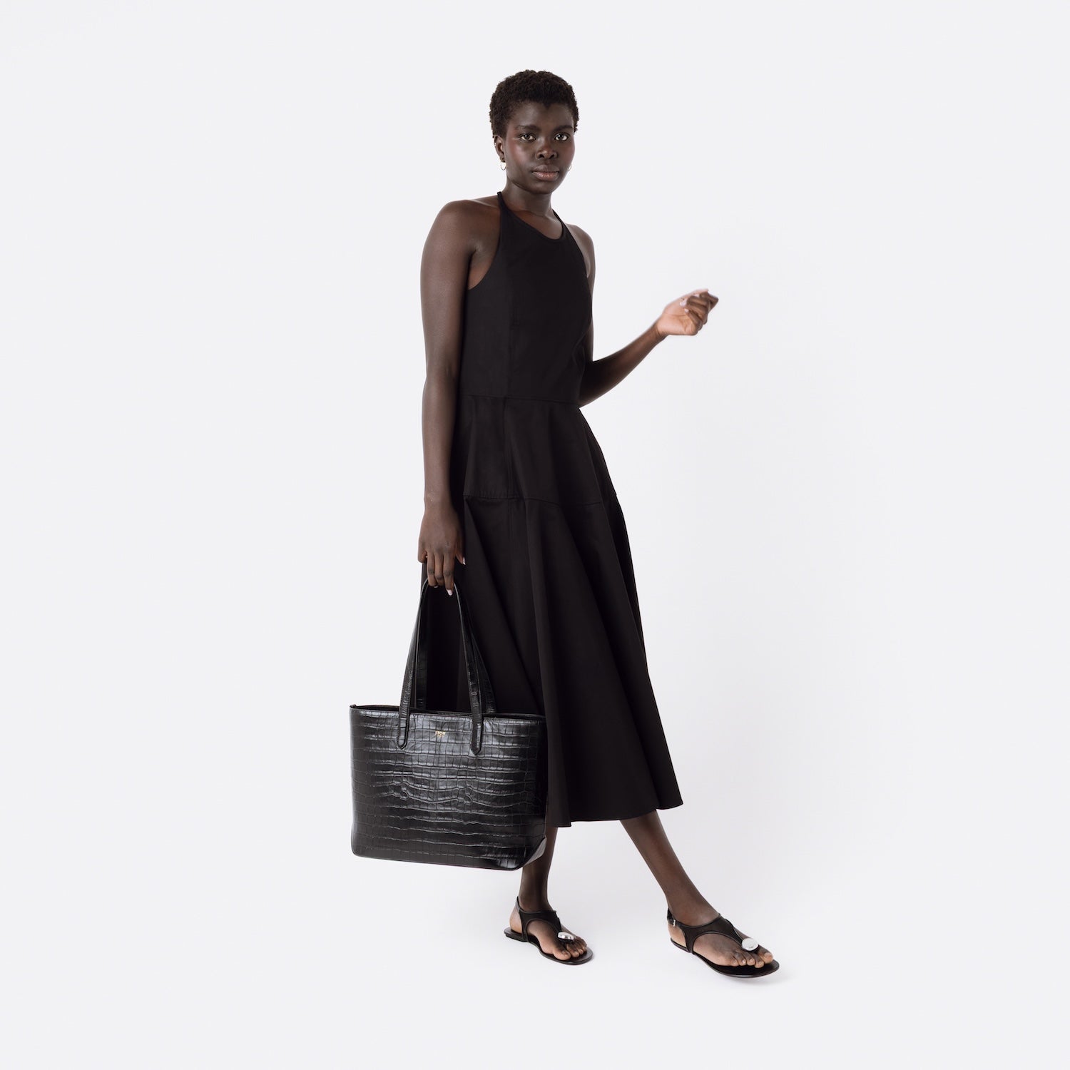 Model holding Stow London's Everyday Tote Bag in Black Embossed Croc leather on a white background featuring gold STOW logo