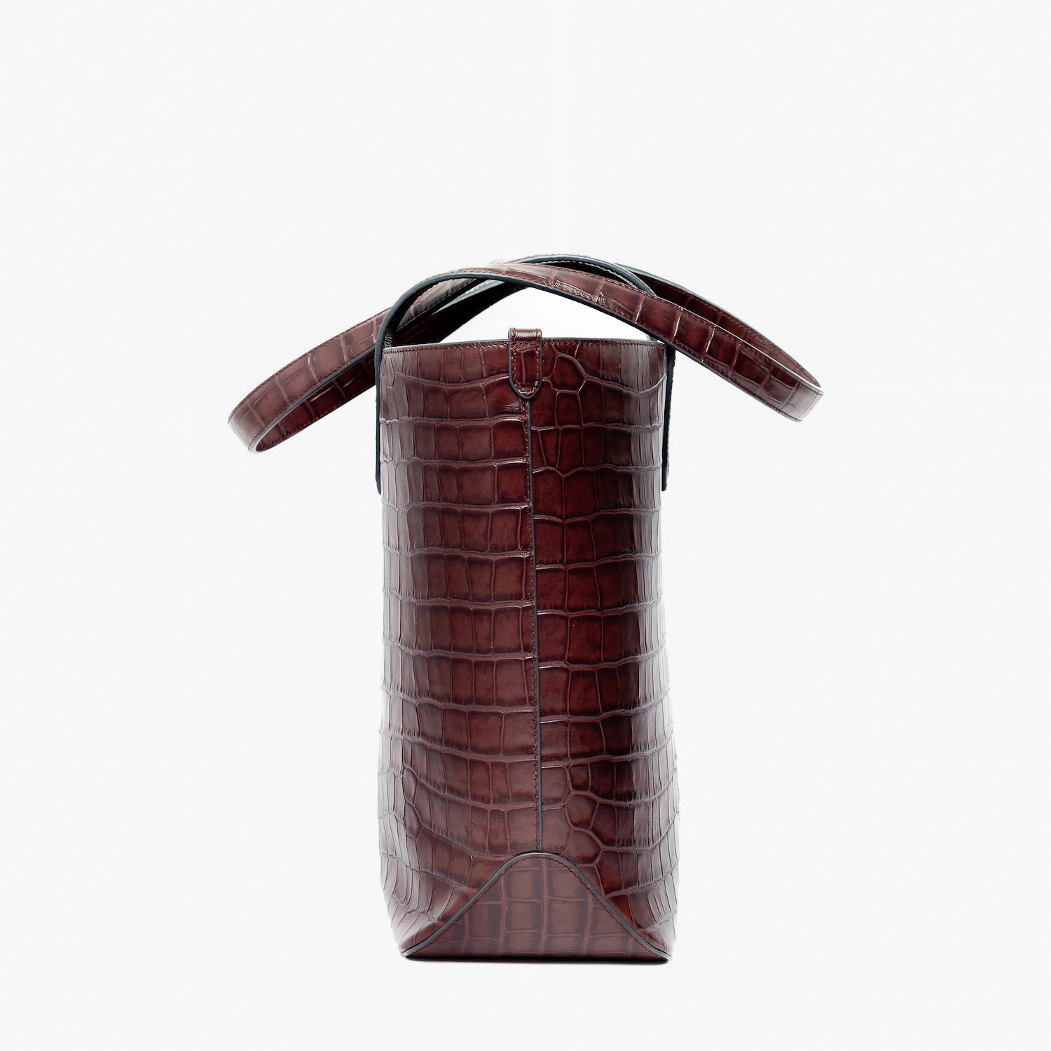 Side view of Stow London's Everyday Tote Bag in Burgundy Embossed Croc leather on a light grey background