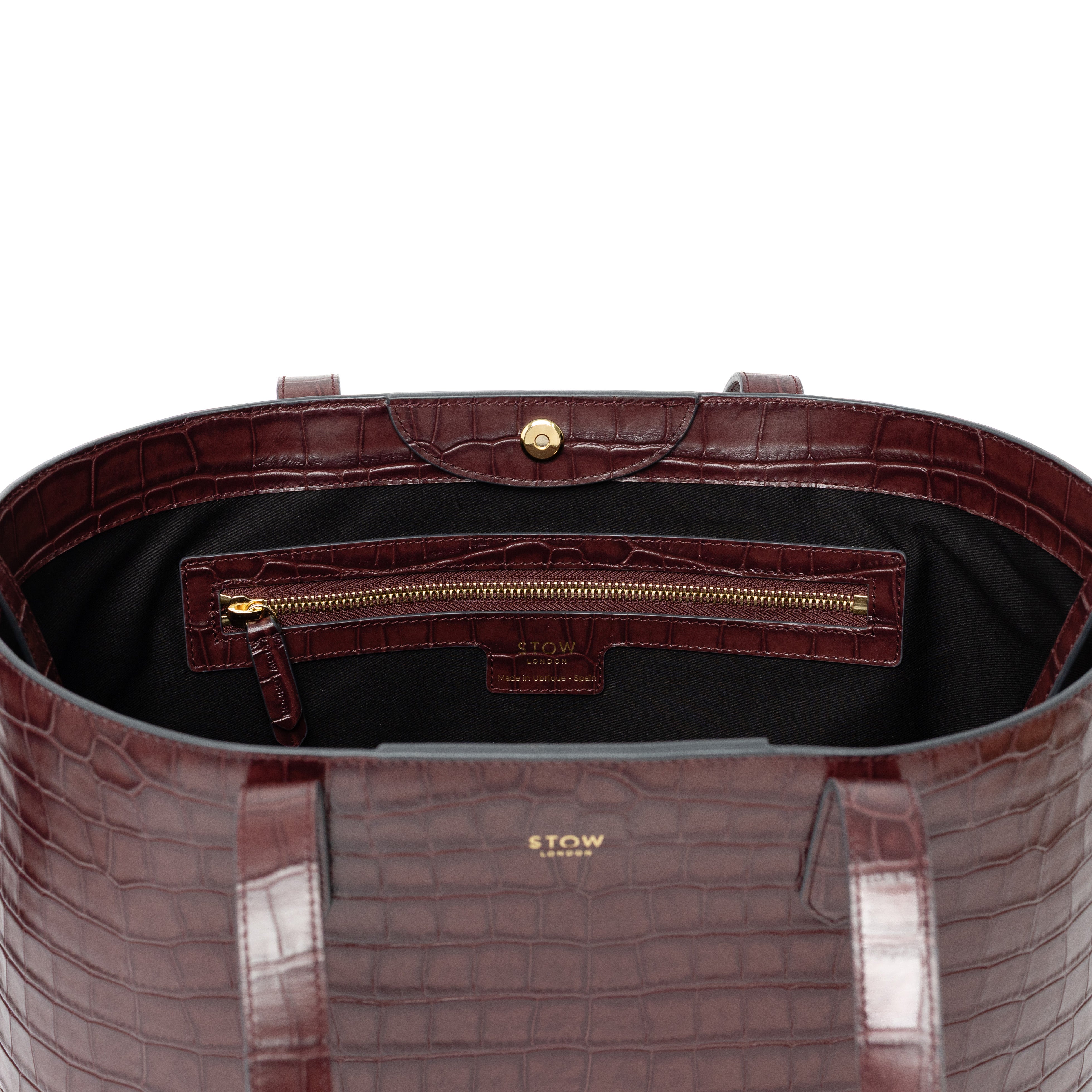 Close up of interior zip pocket and gold hardware on Burgundy Embossed Croc Everyday Tote Bag shown on a white background