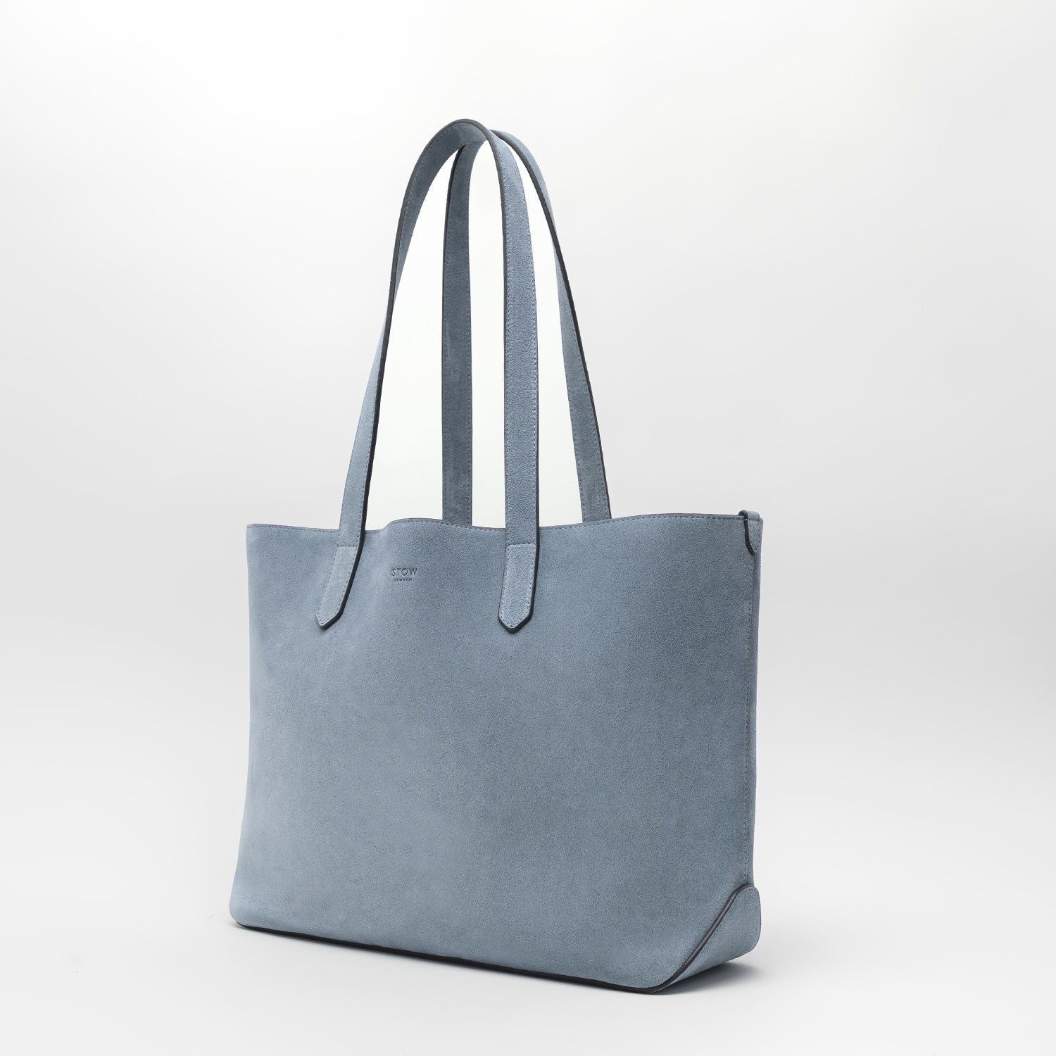 STOW London's Everyday Tote bag in Misty Blue suede on a light grey background featuring a small STOW London logo embossed on the front panel
