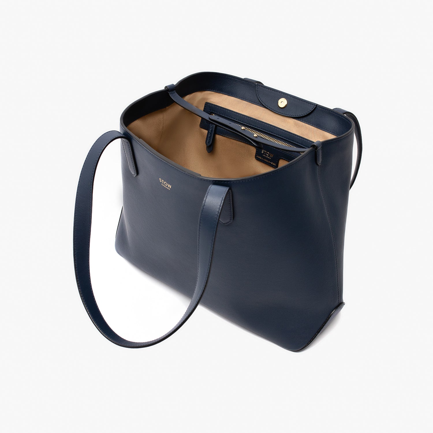 Stow London's Everyday Tote Bag in Navy smooth leather on a light grey background with magnets open showing light beige cotton lining featuring leather strap, magnetic closure and zip pocket