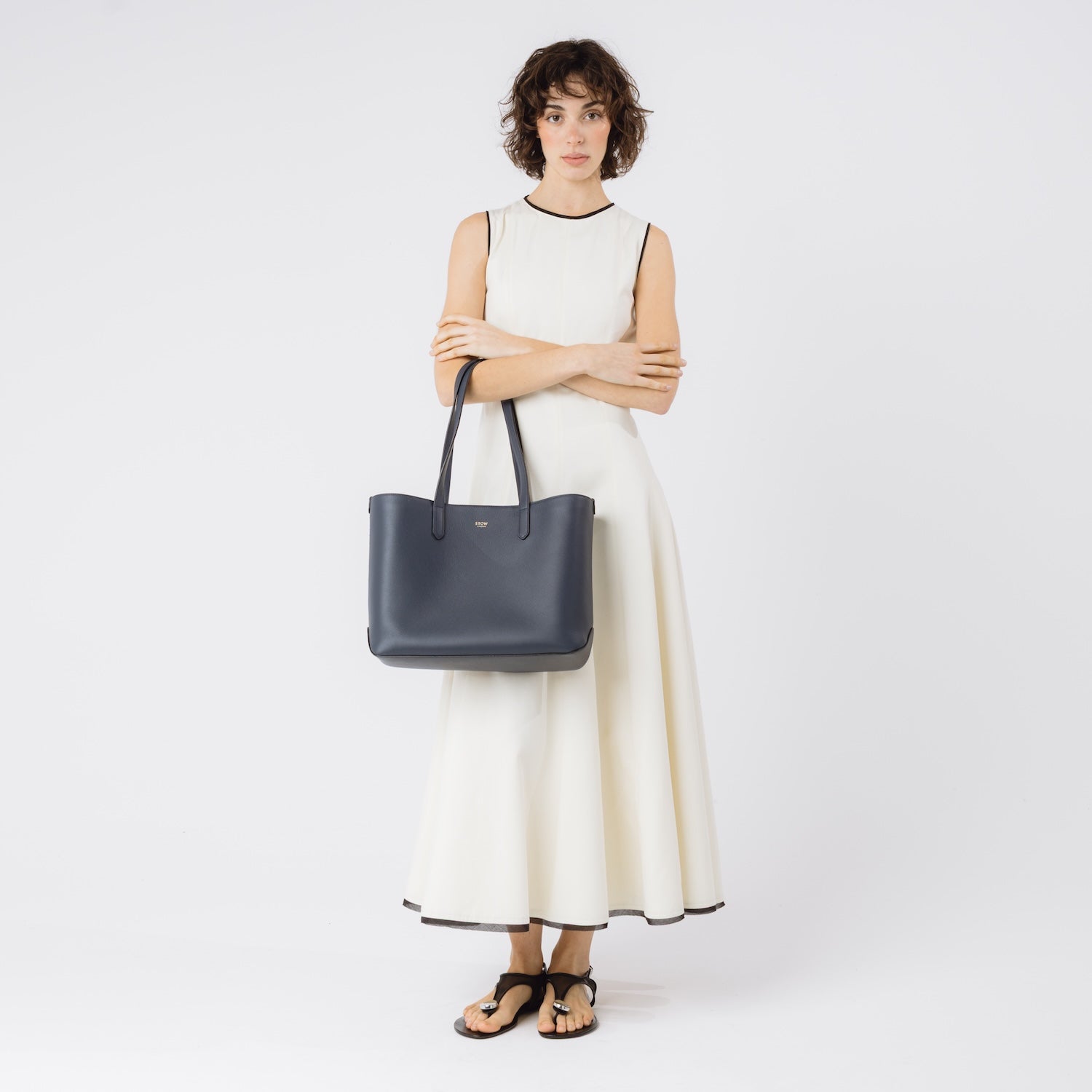 Model wearing Stow London's Everyday Tote Bag in Navy smooth leather on her arm on a white background