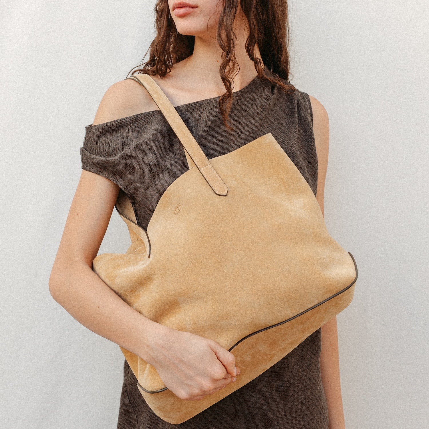 Model wearing STOW London's summer Everyday Tote in Soft Sand Suede, featuring a small embossed STOW London on the front panel