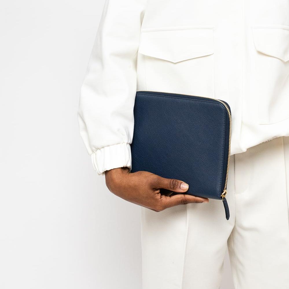 STOW London First Class Folio tech case in Navy leather carried by female model in studio image