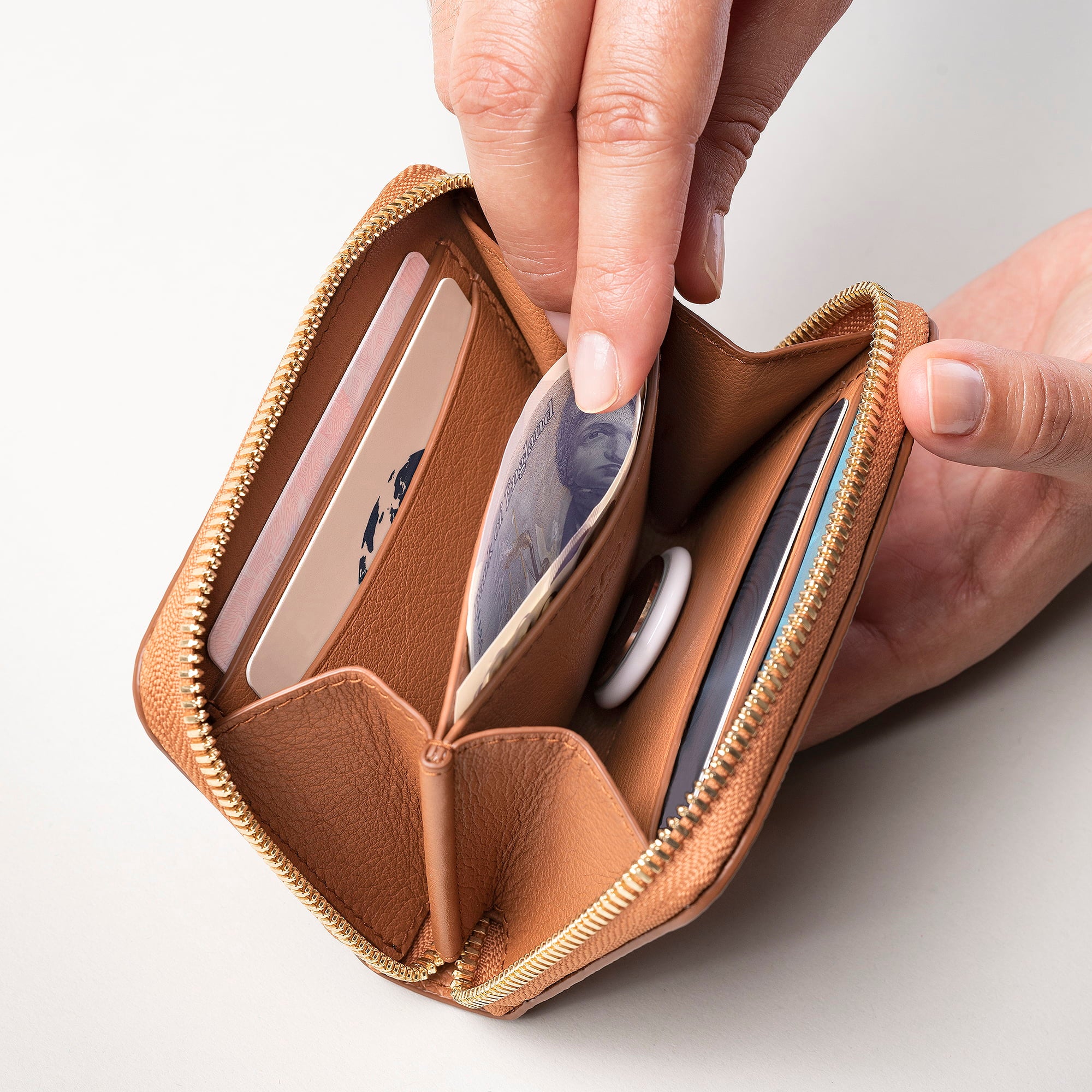STOW Leather Zip Wallet in Earth Tan pebbled leather being held by model, shown open with items inside the wallet.