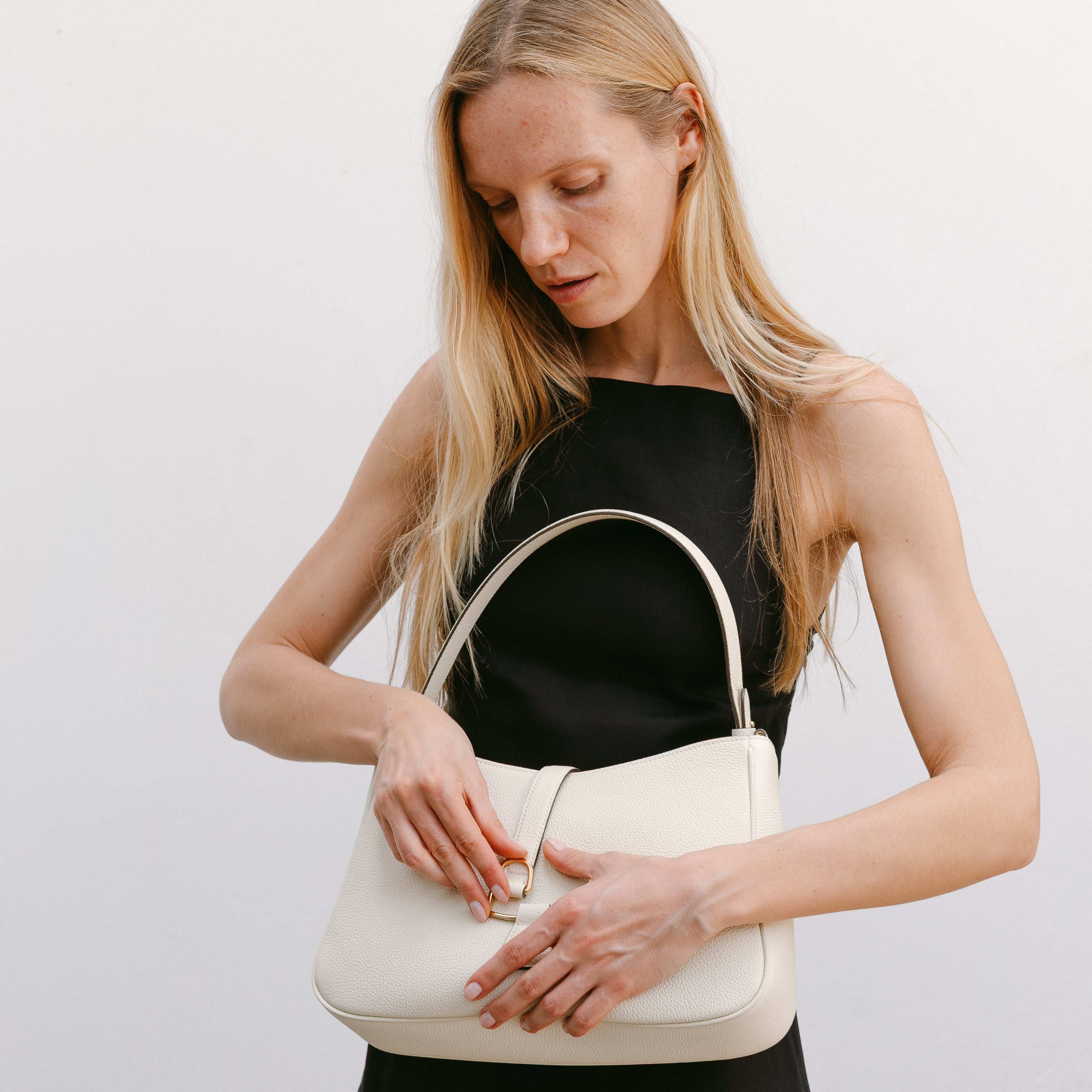 Model with STOW London's Beth Shoulder bag in Spring Moon pebbled leather featuring gold-coated stainless steel hardware and clip on a white background