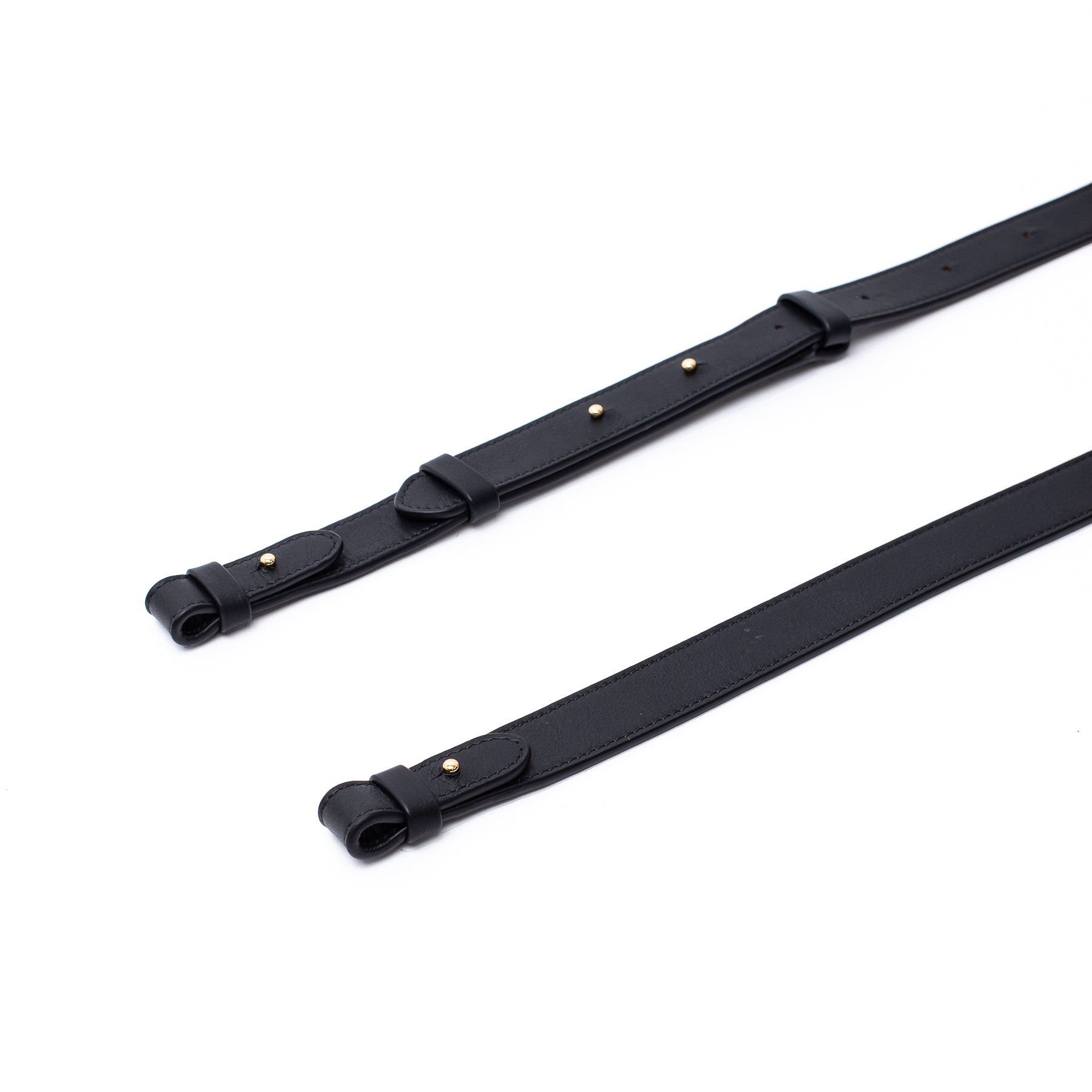 Close up of STOW London's detachable crossbody strap for the Beth bag in Black leather featuring gold stainless steel hardware on a white background