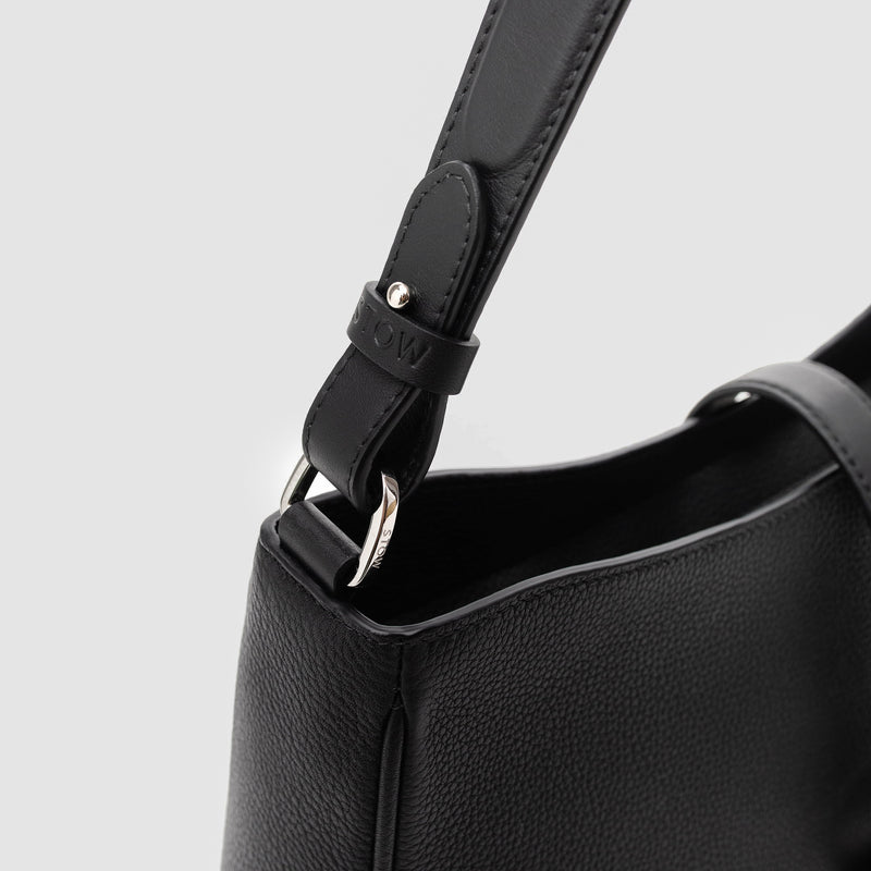 Close up shot of STOW London's Beth bag in Black pebbled and smooth leather featuring the detachable strap and silver stainless steel hardware on a white background