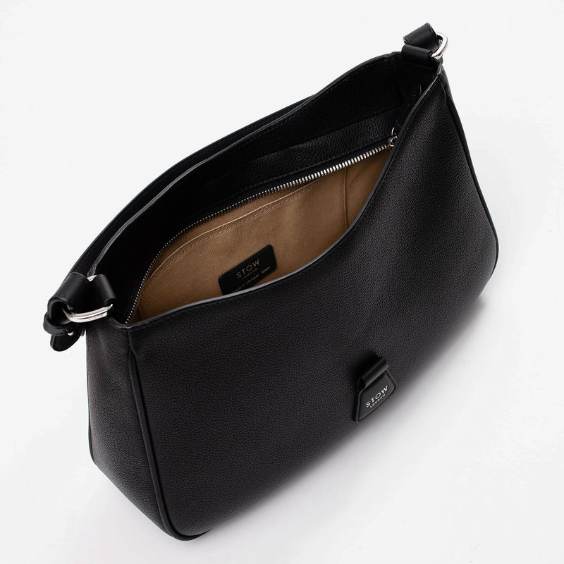 Top angled view of STOW London's Beth bag in Black pebbled and smooth leather with zipper open showing the interior cotton lining and card holder pocket, featuring silver stainless steel hardware on a white background