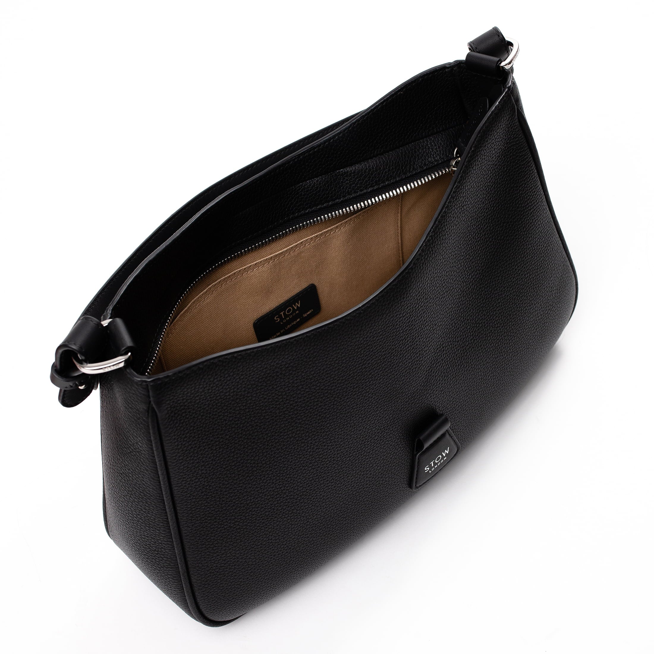 Top angled view of STOW London's Beth bag in Black pebbled and smooth leather with zipper open showing interior cotton lining and card holder pocket featuring silver stainless steel hardware on a white background