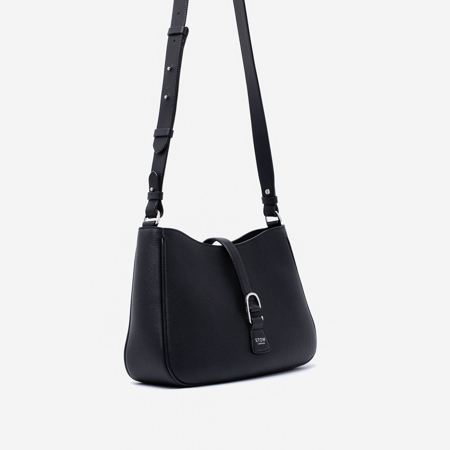 Off-axis view of STOW London's Beth bag and detachable crossbody strap in Black leather featuring silver stainless steel hardware on a white background