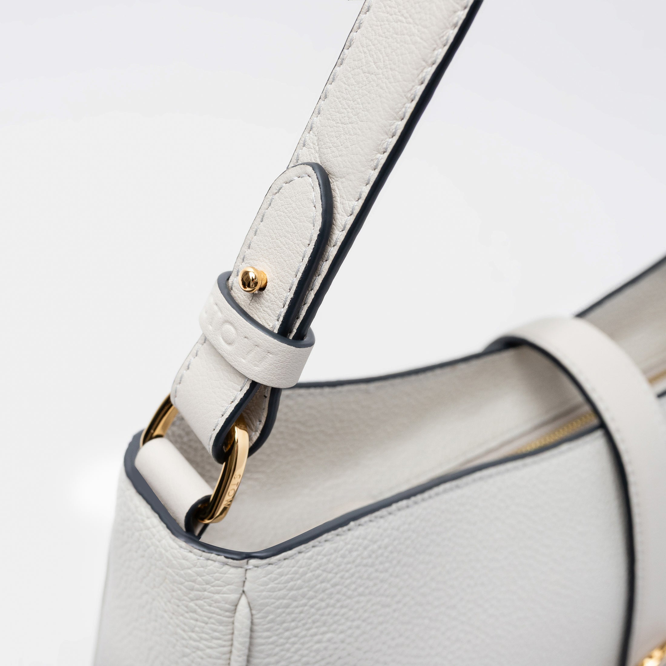 Close up shot of STOW London's Beth bag in Cloud Grey pebbled and smooth leather featuring the detachable strap and gold-coated, stainless steel hardware on a white background