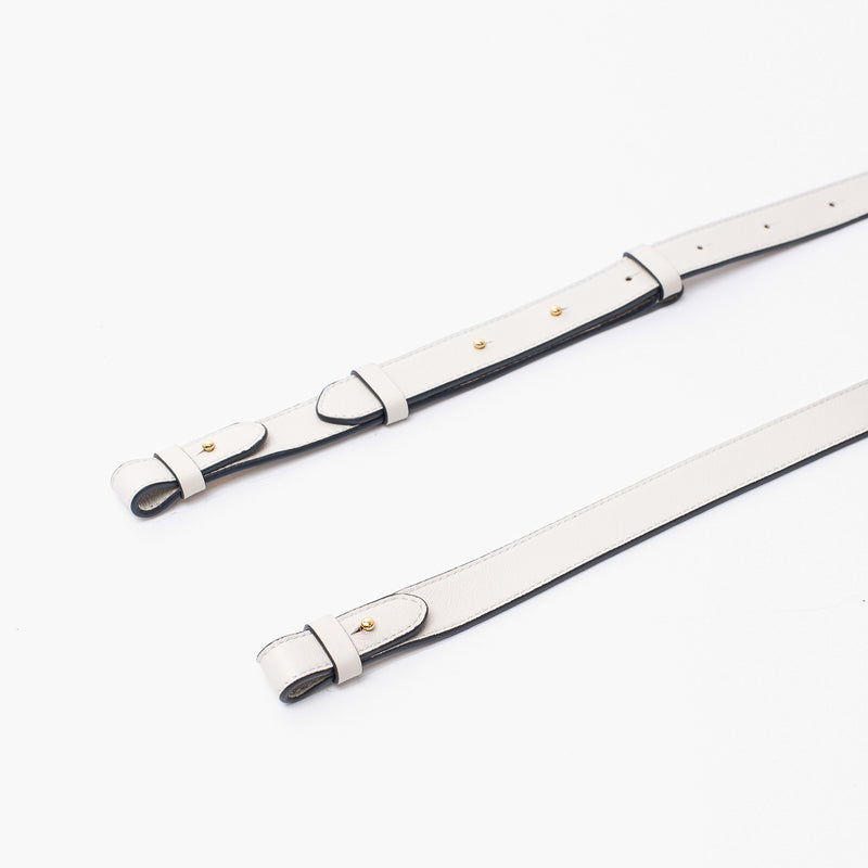 Close up of STOW London's detachable crossbody strap for the Beth bag in Cloud Grey leather featuring gold stainless steel hardware on a white background