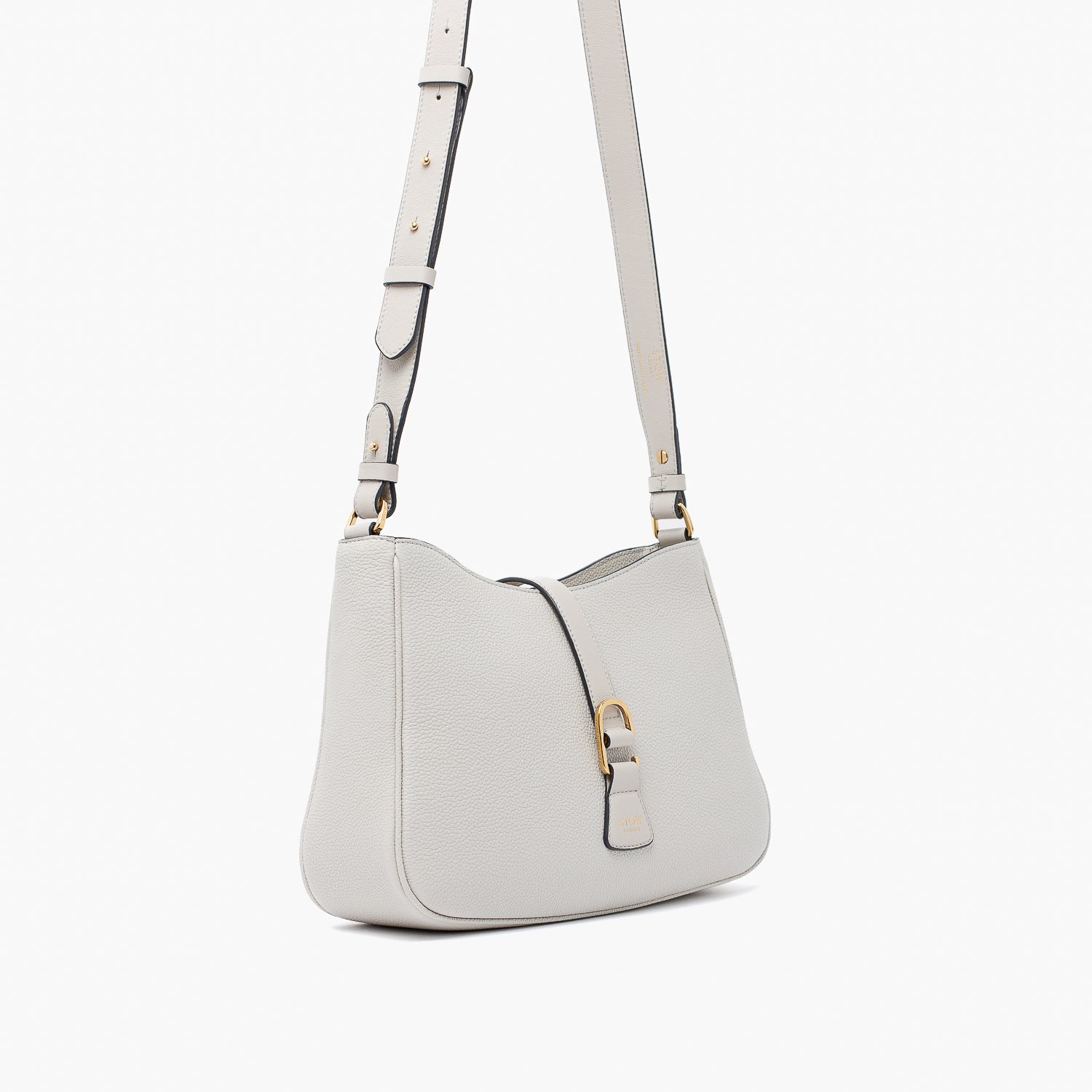 Off-axis view of STOW London's Beth bag and detachable crossbody strap in Cloud Grey leather featuring gold stainless steel hardware on a white background