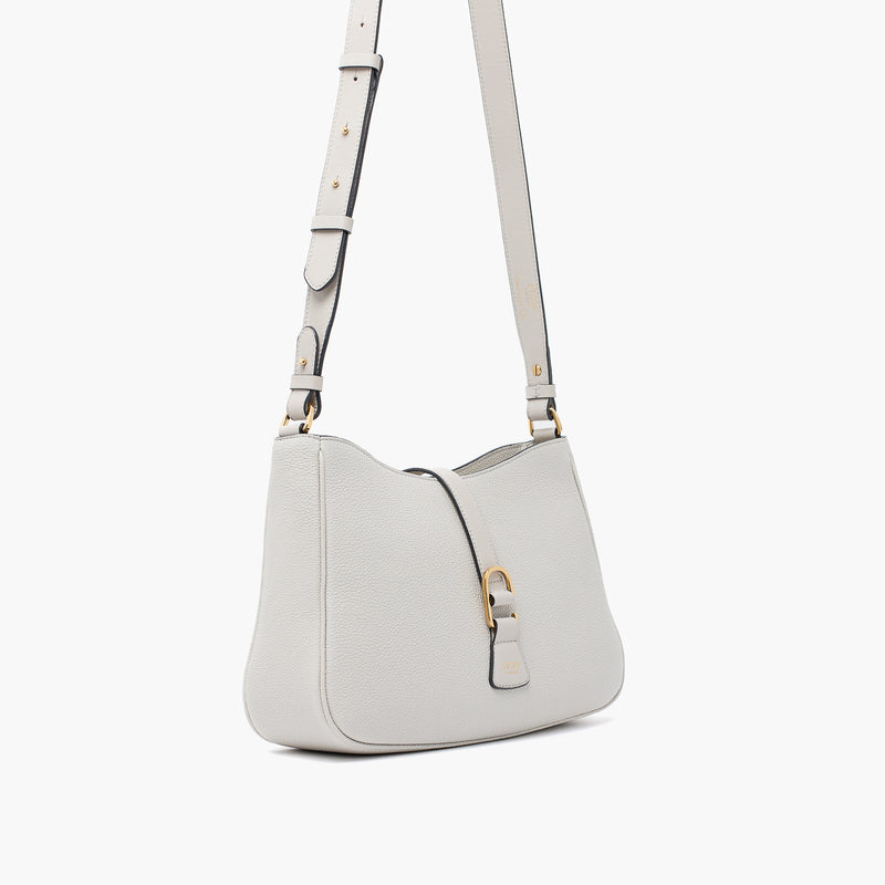 Off-axis view of STOW London's Beth bag and detachable crossbody strap in Cloud Grey leather featuring gold stainless steel hardware on a white background
