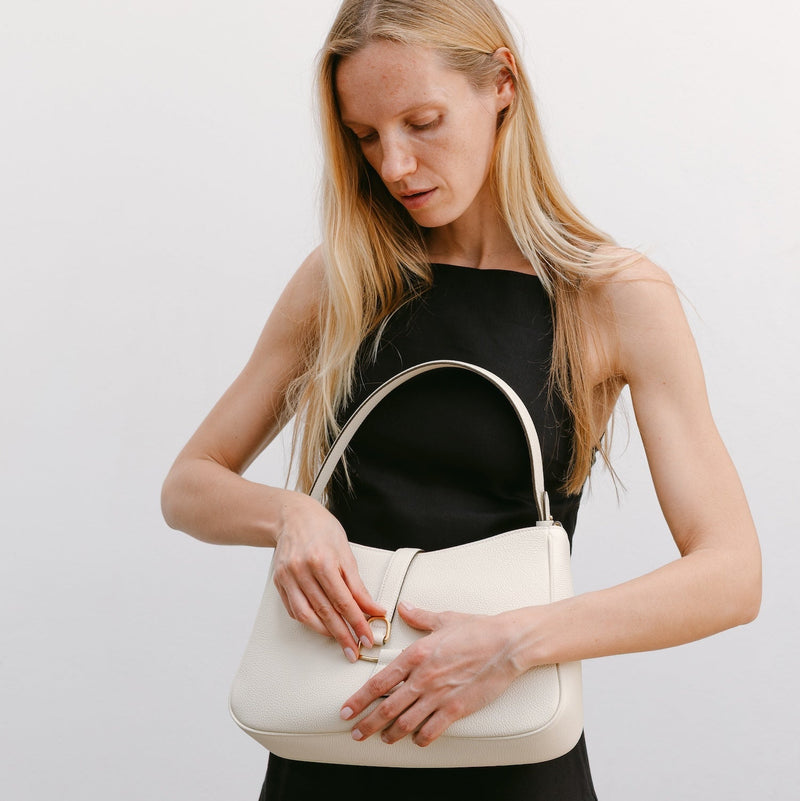 Model with STOW London's Beth Shoulder bag in Spring Moon pebbled leather featuring gold-coated stainless steel hardware and clip on a white background