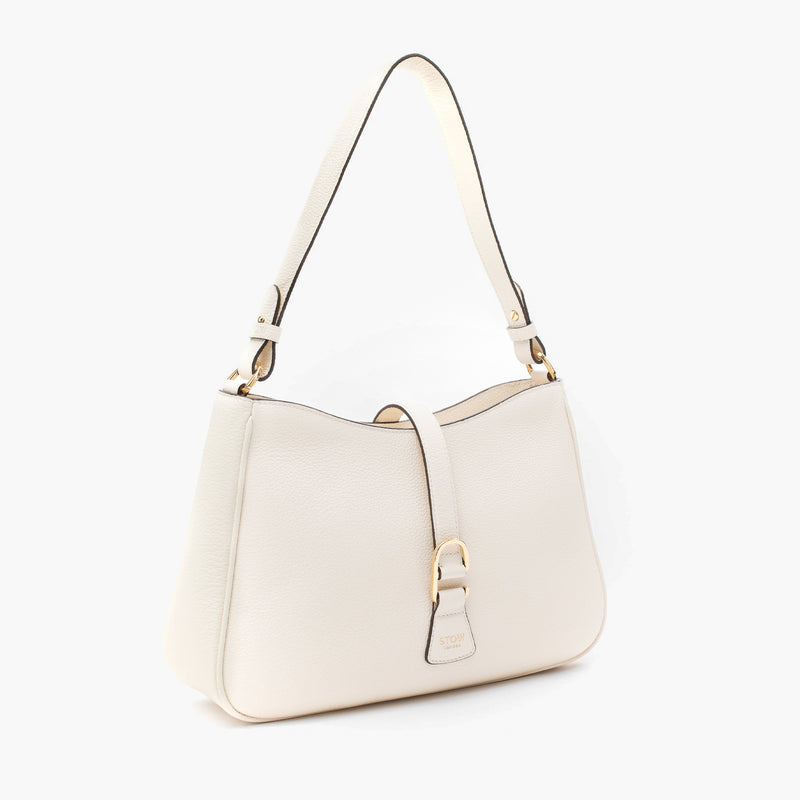 Off-axis view of STOW London's Beth bag in Spring Moon pebbled and smooth leather featuring gold-coated stainless steel hardware and clip on a white background