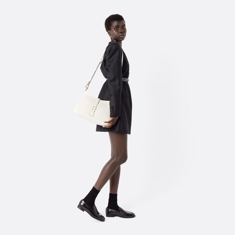 Model wearing STOW London's Beth bag by its detachable crossbody strap in Spring Moon leather featuring gold stainless steel hardware on a white background