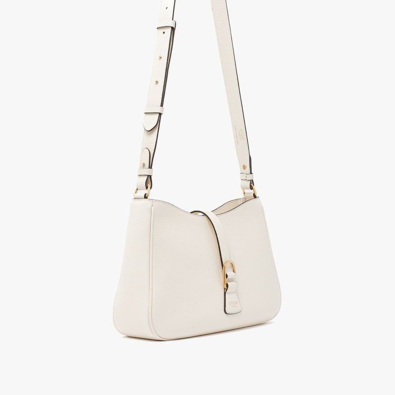 Off-axis view of STOW London's Beth bag and detachable crossbody strap in Spring Moon leather featuring gold stainless steel hardware on a white background