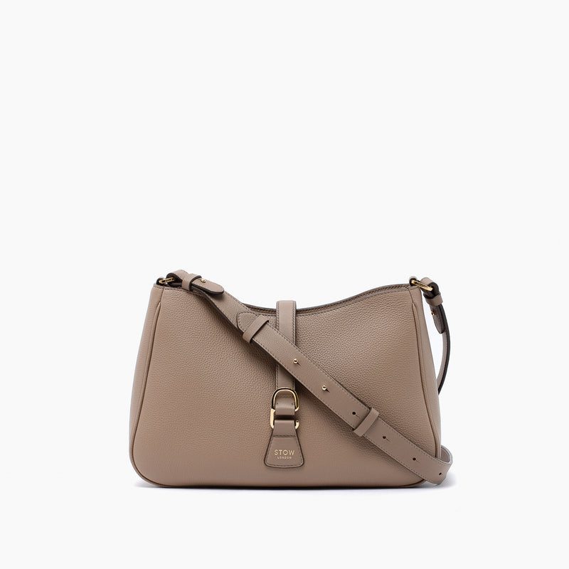 STOW London's Beth bag and detachable crossbody strap in Warm Taupe leather featuring gold stainless steel hardware on a white background