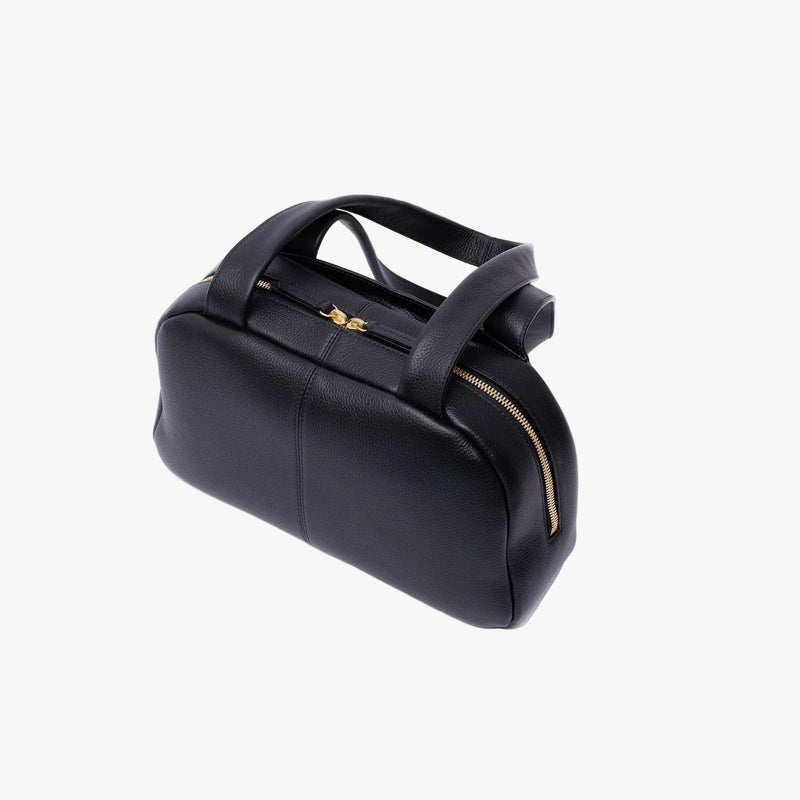 Top view of STOW London's Bowling bag in Black pebbled leather featuring gold-coated stainless steel hardware and zip on a light grey background