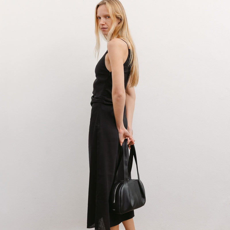 Model with STOW London's Bowling bag in Black pebbled leather featuring the pleated front panel and silver stainless steel hardware 