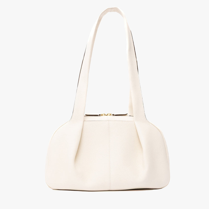 STOW London's Bowling bag in Spring Moon pebbled leather featuring the pleated front panel and gold-coated stainless steel hardware on a light grey background