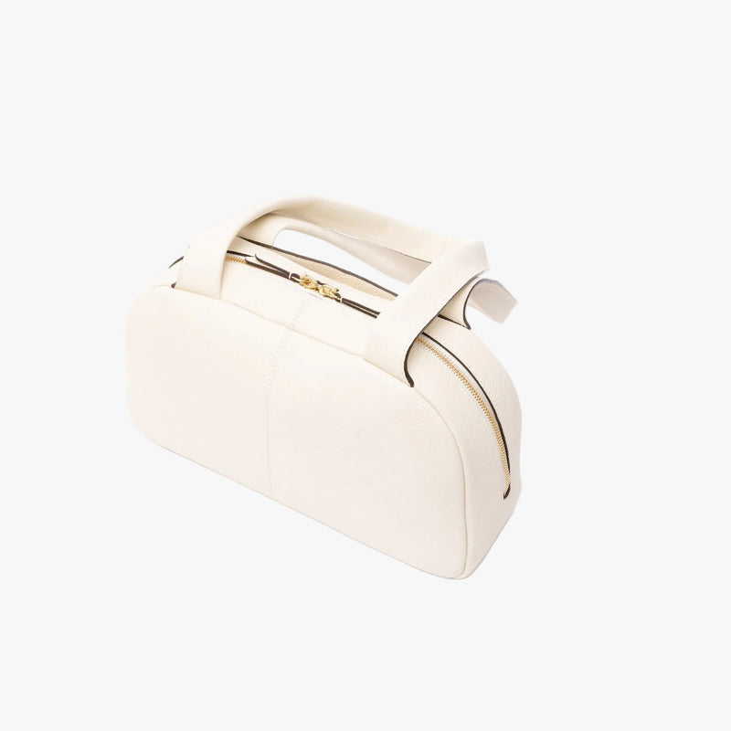 Top view of the back of STOW London's Bowling bag in Spring Moon pebbled leather featuring gold-coated stainless steel hardware on a light grey background