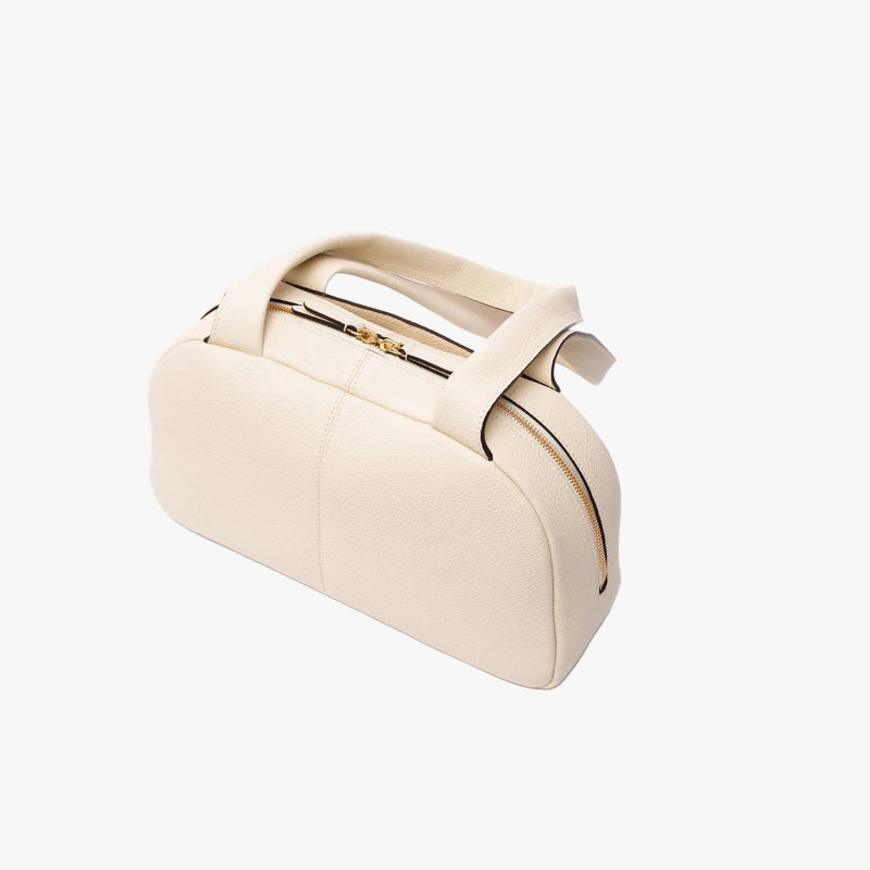 Back panel of STOW London's Bowling bag in Spring Moon pebbled leather featuring gold-coated stainless steel hardware on a light grey background