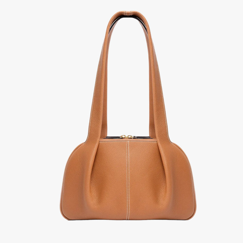 STOW London's Bowling bag in Earth Tan pebbled leather featuring the pleated front panel and gold-coated stainless steel hardware on a light grey background