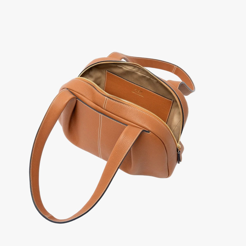 STOW London's Bowling bag in Earth Tan pebbled leather on a light grey background with zipper open showing the cotton interior and leather slip pocket 