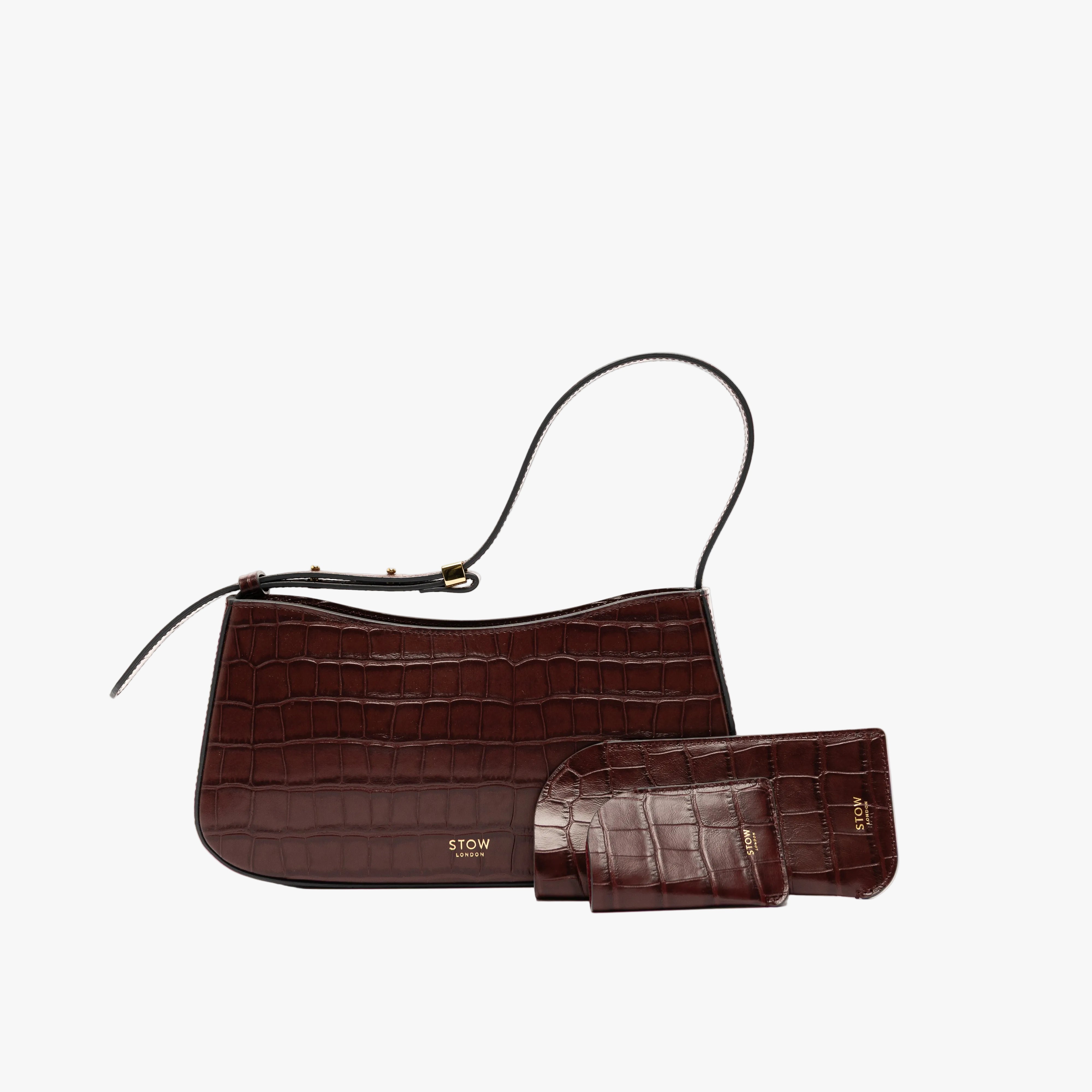 STOW London's Mini Cardholder, Glasses Case and Post Shoulder in Burgundy Embossed Croc leather on a light grey background featuring a small gold embossed logos on the front