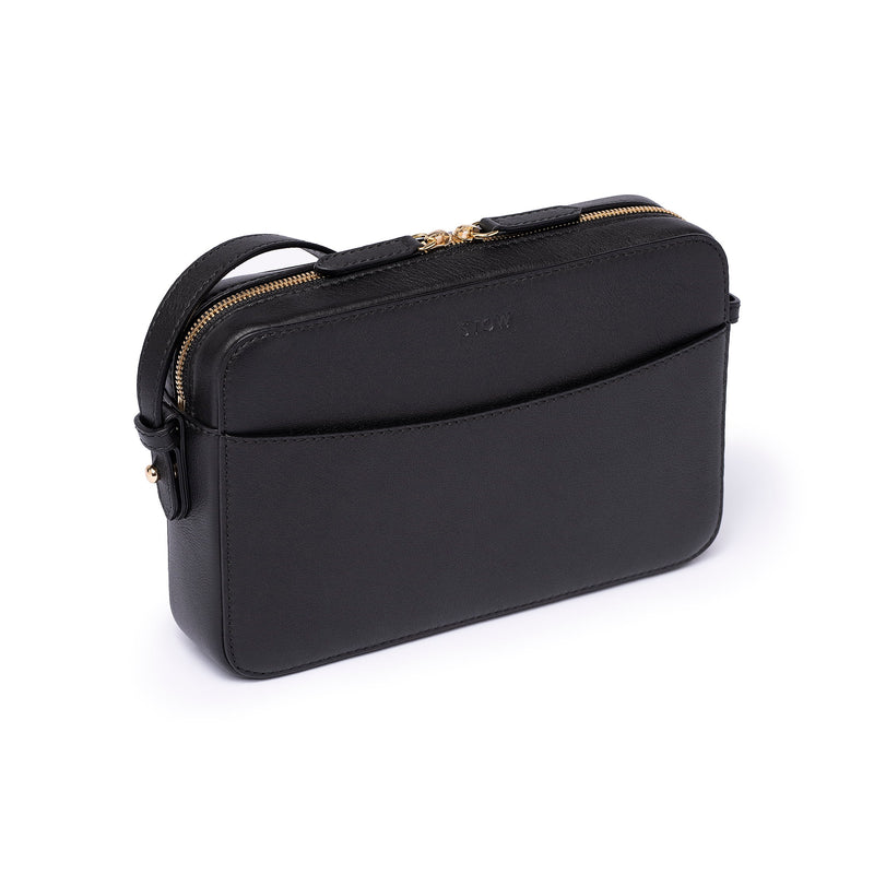 Black leather Camera Bag by STOW, studio image showing bag diagonally with crossbody strap.