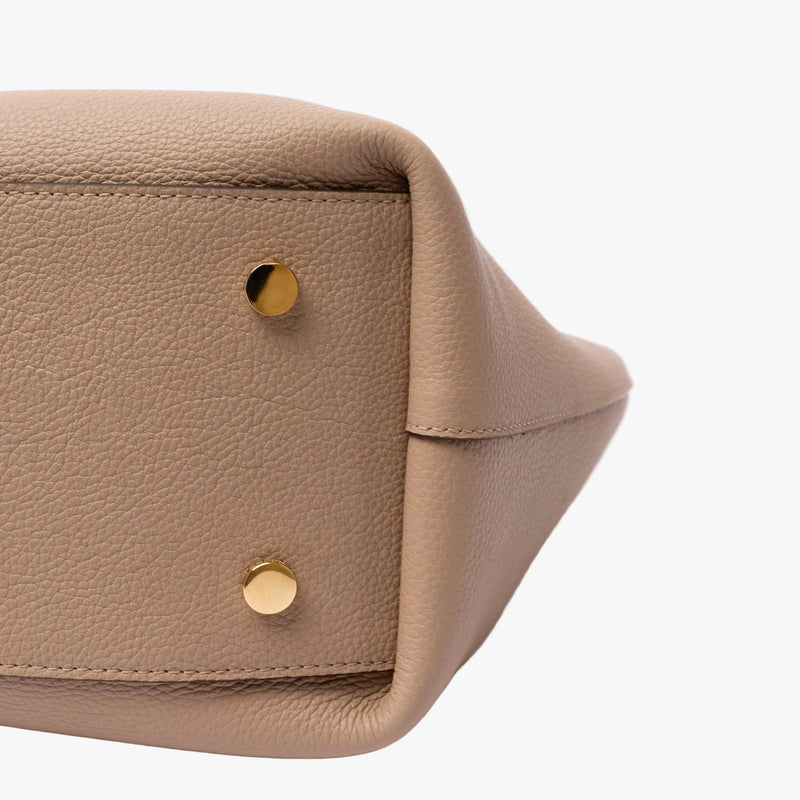 Close up of the base panel on STOW London's Hobo Tote in Camel pebbled leather featuring the gold-coated stainless steel protective feet.