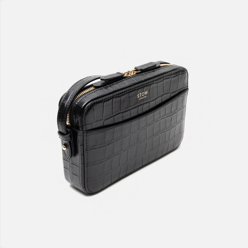 Off-axis view of STOW London's Camera bag in Black Embossed Croc leather featuring gold-coated stainless steel hardware on a white background