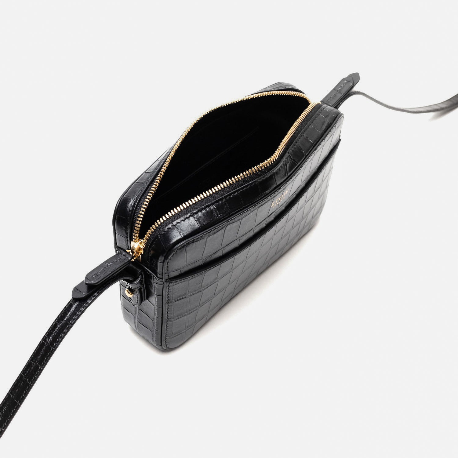 Top angled view of STOW London's Camera bag in Black Embossed Croc leather with zipper open featuring gold-coated stainless steel hardware on a white background