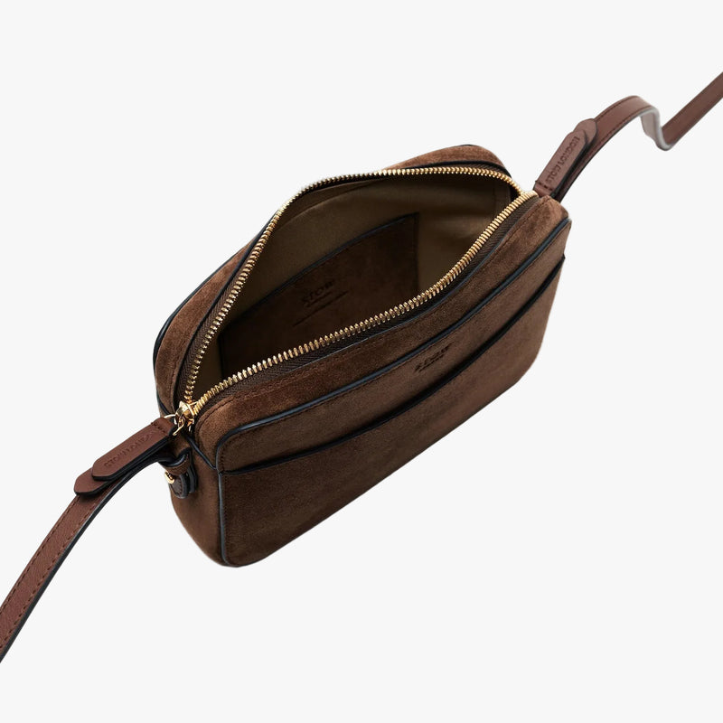 STOW London's Camera bag in Chocolate Suede leather with detachable crossbody strap on a light grey background with zipper open showing cotton interior and leather slip pocket