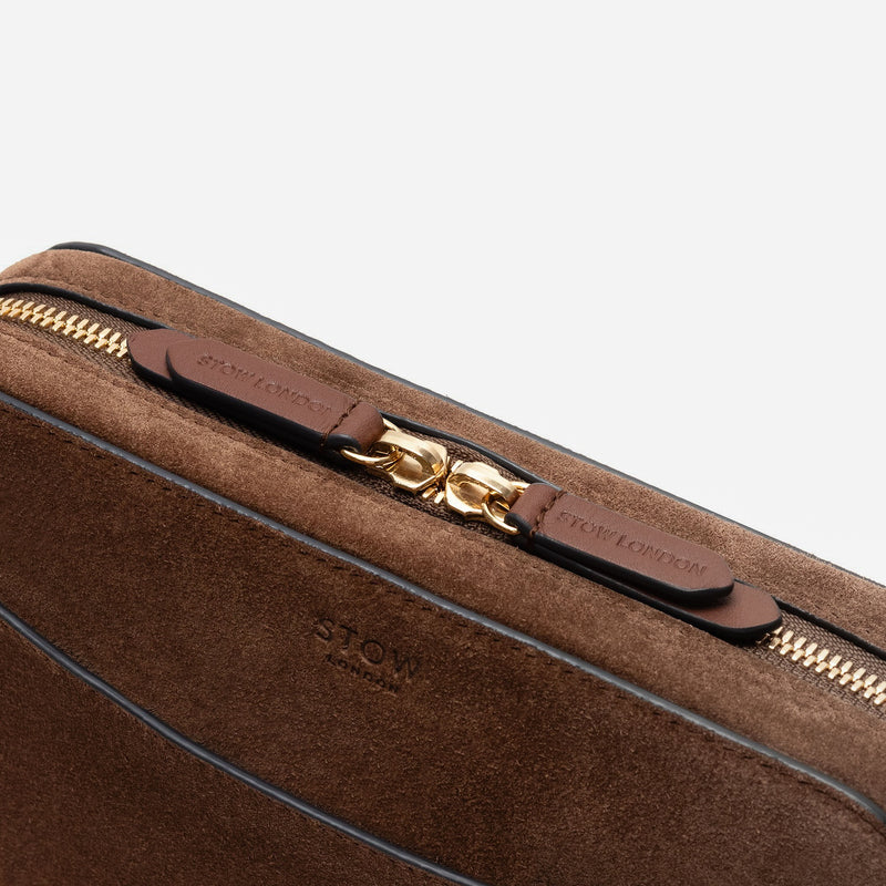 Close up of zip and brand engraved pull tabs on STOW London's Camera bag in Chocolate Suede leather featuring gold-coated stainless steel hardware on a white background