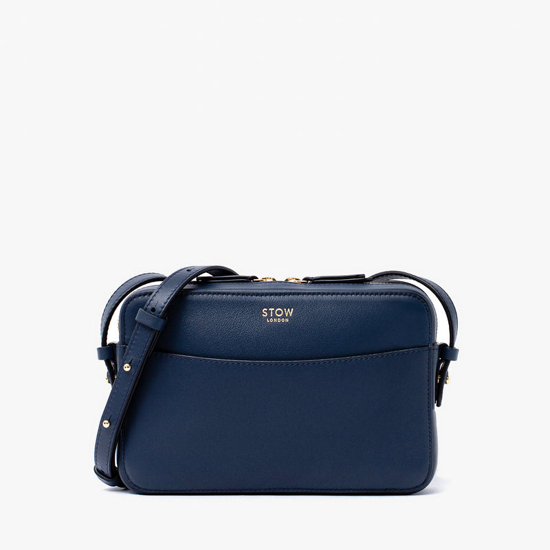 STOW London's Camera bag in Navy smooth leather with detachable crossbody strap featuring gold-coated stainless steel hardware on a white background