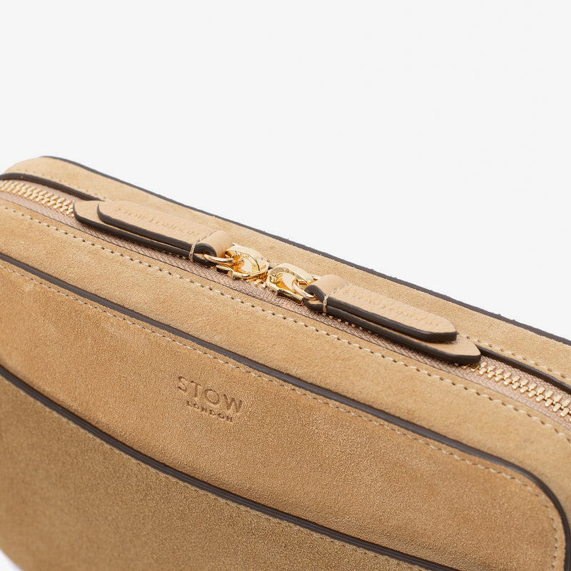 Close up of zip and brand engraved pull tabs on STOW London's Camera bag in Soft Sand Suede leather featuring gold-coated stainless steel hardware on a white background